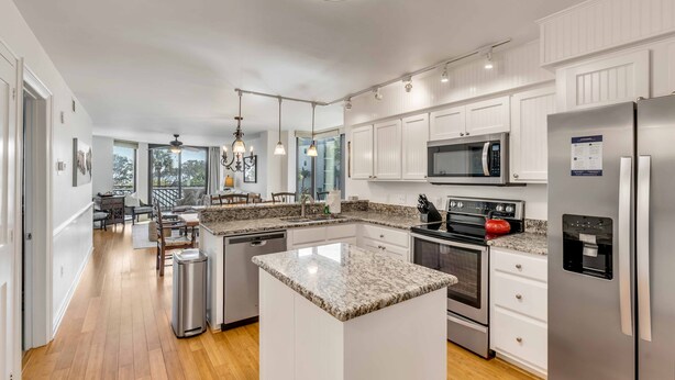 A modern kitchen with white cabinetry, granite countertops, stainless steel appliances, and a central island.