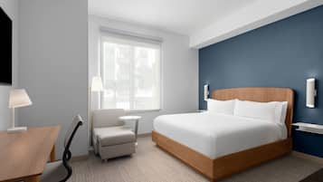 Una habitación de hotel con cama, escritorio, silla, mesita y ventana.