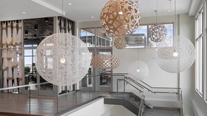 A modern interior with a glass railing, a staircase, and decorative spherical light fixtures. - Element by Marriott Tampa Midtown (Tampa)