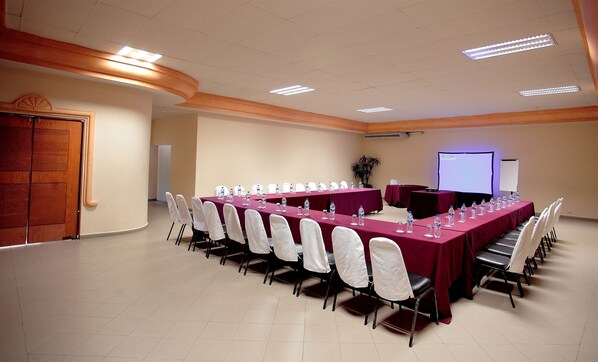 A conference room with a long table, chairs, a projector screen, and a whiteboard.