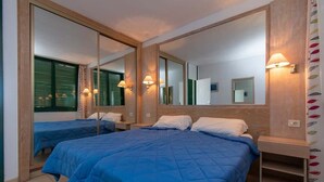 Ett hotellrum med två separata sängar, en stor spegel, sänglampor och ett litet träbord vid sängen.