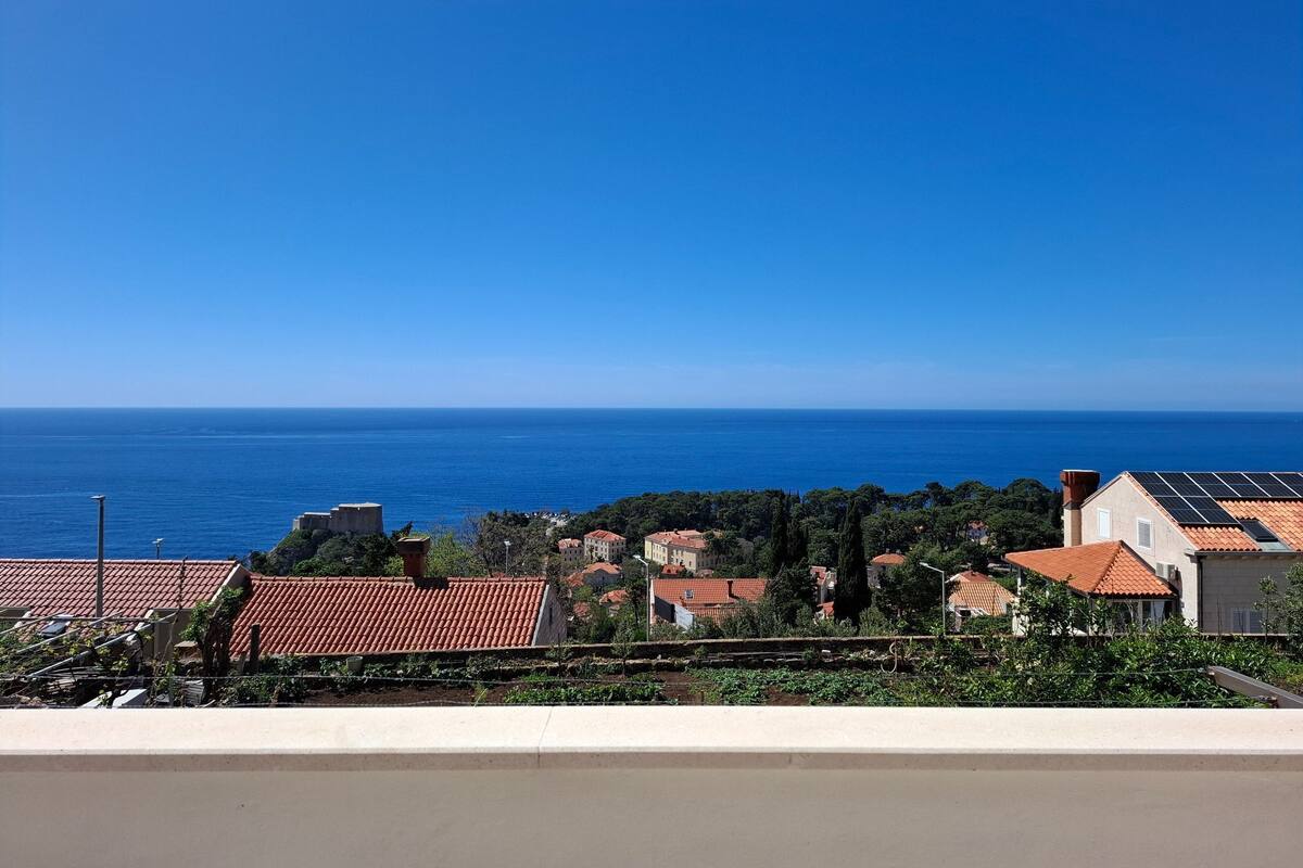 A coastal view with buildings, a clear blue sky, and the sea in the background.