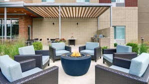 An outdoor patio with wicker furniture, a central fire pit, and a covered seating area. - TownePlace Suites by Marriott Columbus Dublin (Dublin)