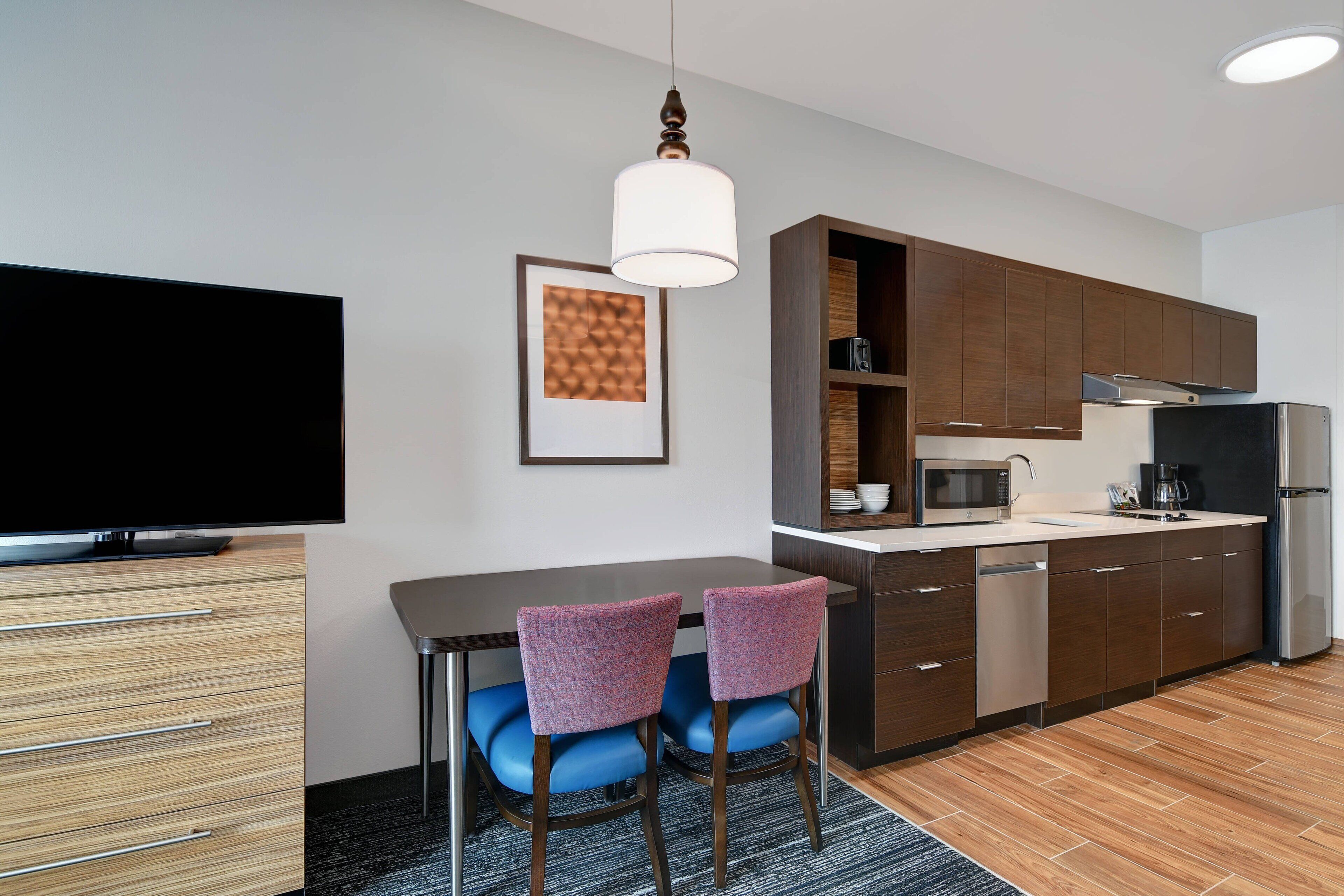 A modern kitchen with a dining area, a flat-screen TV, and a microwave.