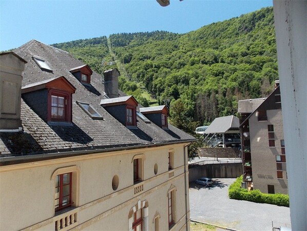 A building with multiple windows and a sloped roof, surrounded by lush green hills. - Lovely 2BR Apartment for 7 with Wi-Fi and Parking in Luchon (Bagnères-de-Luchon)