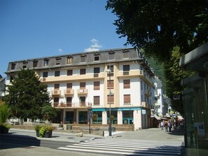 Un edificio de varios pisos con un local comercial en la planta baja, que incluye un banco y una cafetería.