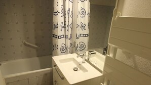 Un baño pequeño con bañera, lavamanos y cortina de ducha con un diseño sencillo.