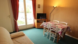 Una habitación acogedora con cama, una mesa de comedor con sillas, un televisor y una lámpara.