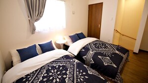 Quarto com duas camas, uma janela com cortinas, ar condicionado e porta de madeira.
