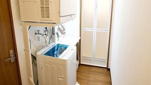 Quarto compacto com máquina de lavar, secadora e pequeno armário.