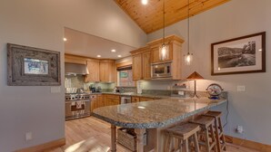 A kitchen with wooden cabinets, a granite countertop, a built-in oven, and a large island with stools.