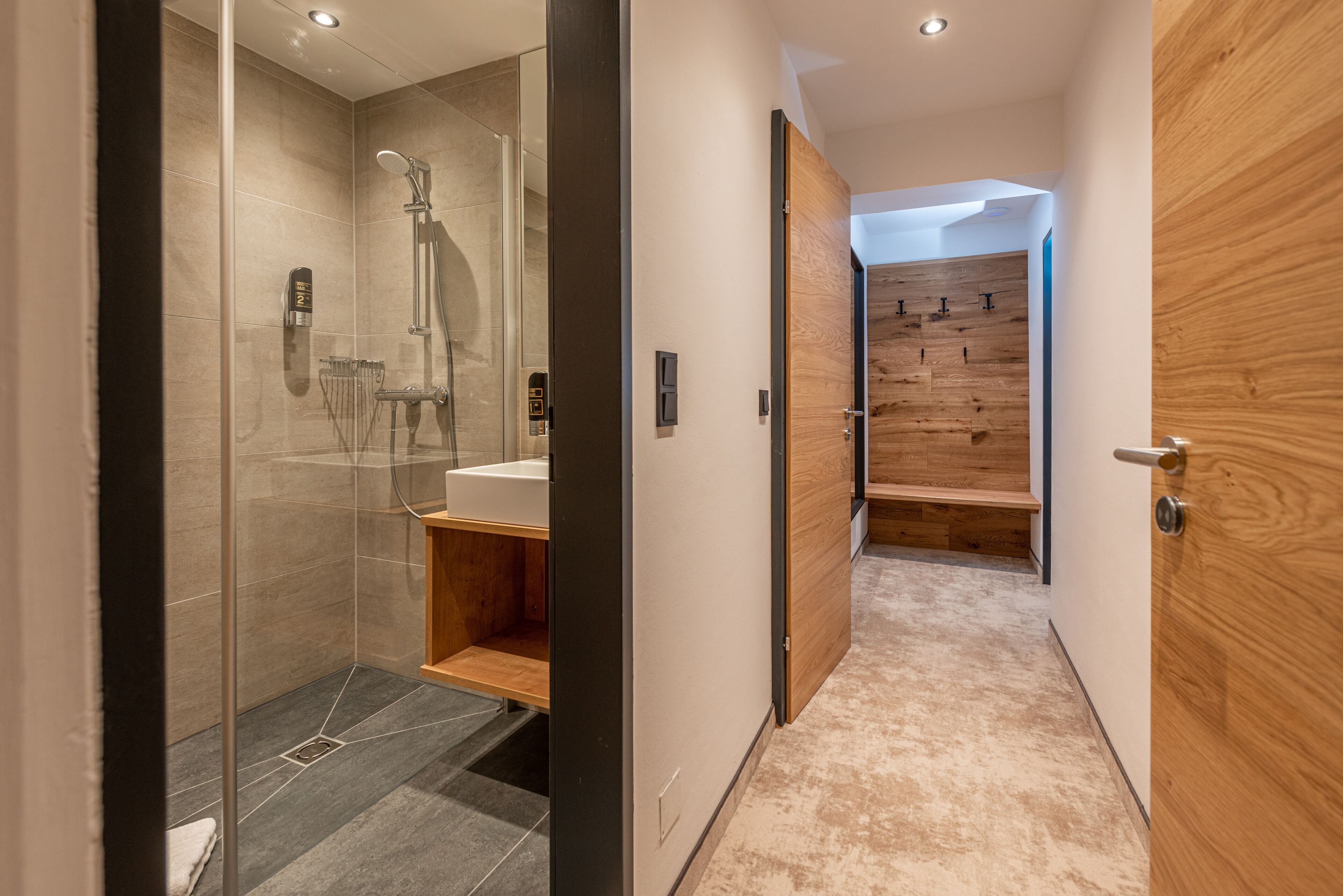 A modern bathroom with a glass shower enclosure, a wooden vanity, and a showerhead.