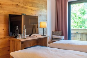 A wooden room with a bed, a TV, a lamp, and a window with curtains. - Stadtvilla Schladming Boutiquehotel (Schladming)