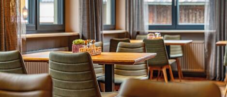 A dining area with wooden tables and green upholstered chairs.