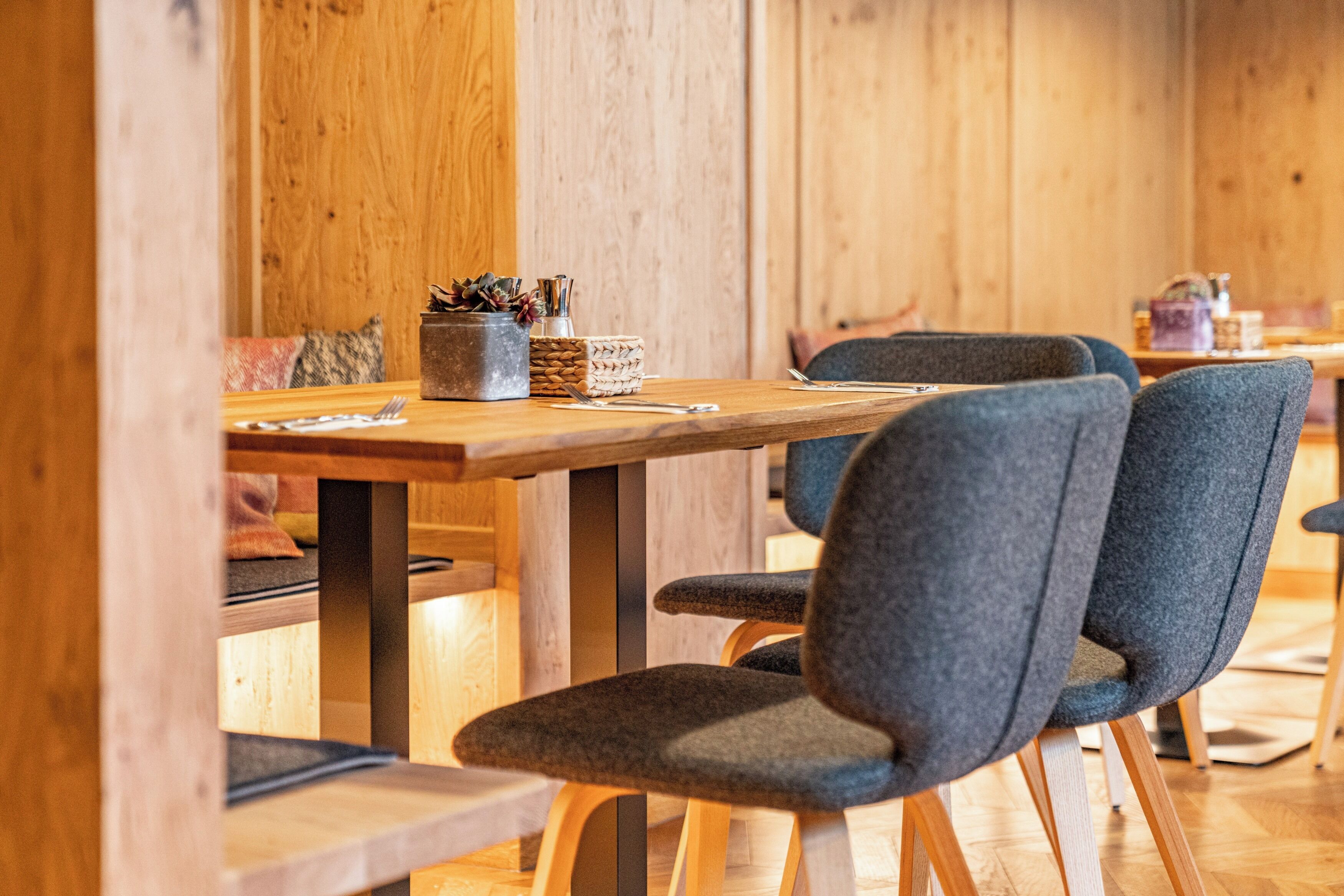 Zona pranzo in legno con tavolo, sedie e un cesto di posate.