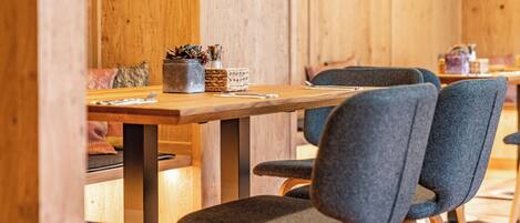 Un comedor de madera con una mesa, sillas y una cesta de utensilios.
