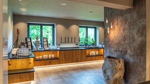 A modern bar area with a wooden counter, glassware, and a stone sink. - Stadtvilla Schladming Boutiquehotel (Schladming)