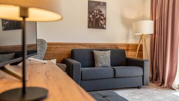 Ein modernes Wohnzimmer mit grauem Sofa, einem Holzsideboard und einer Stehlampe.