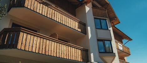 A multi-story building with wooden balconies and large windows.