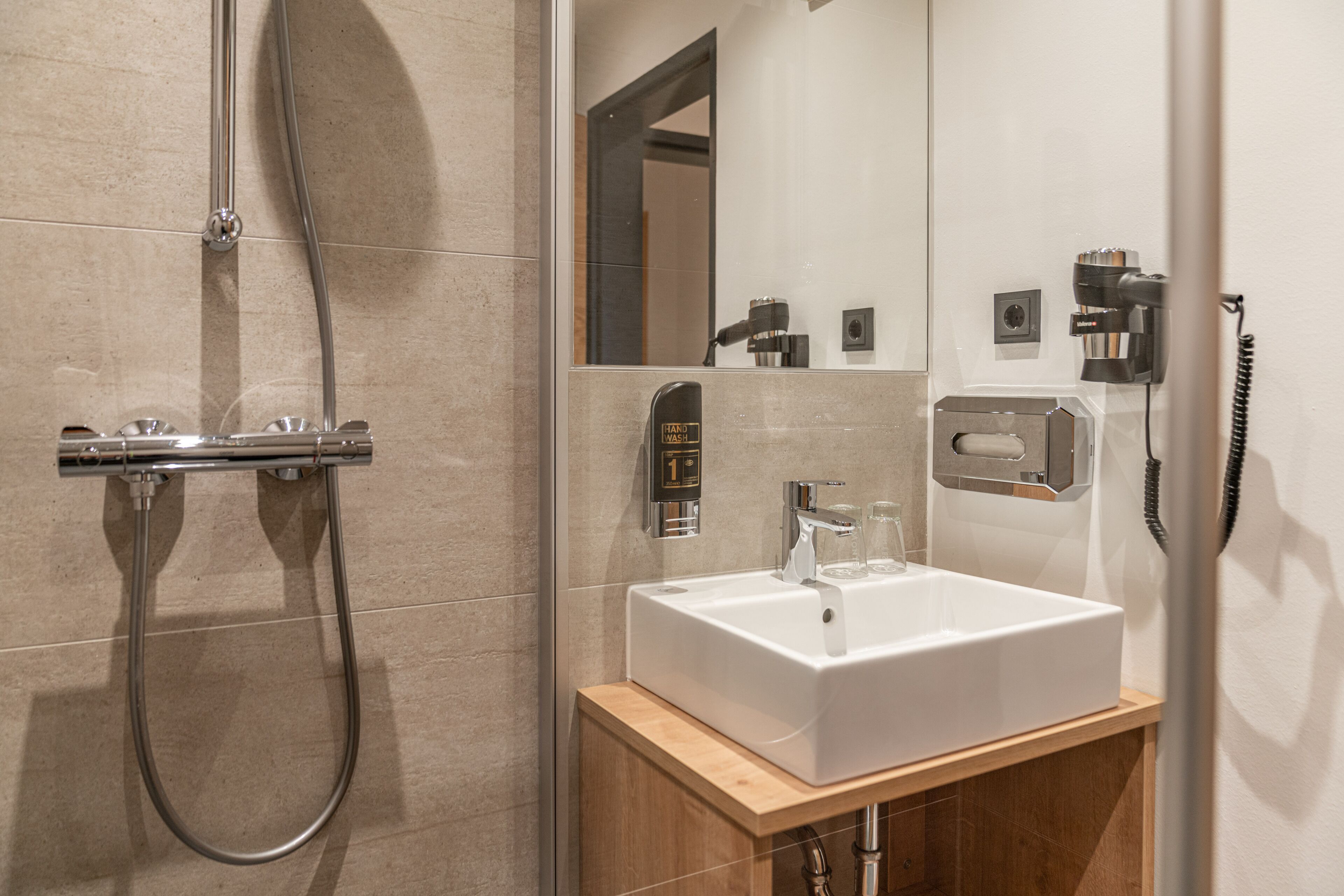 A modern bathroom with a shower, a sink, and a mirror.
