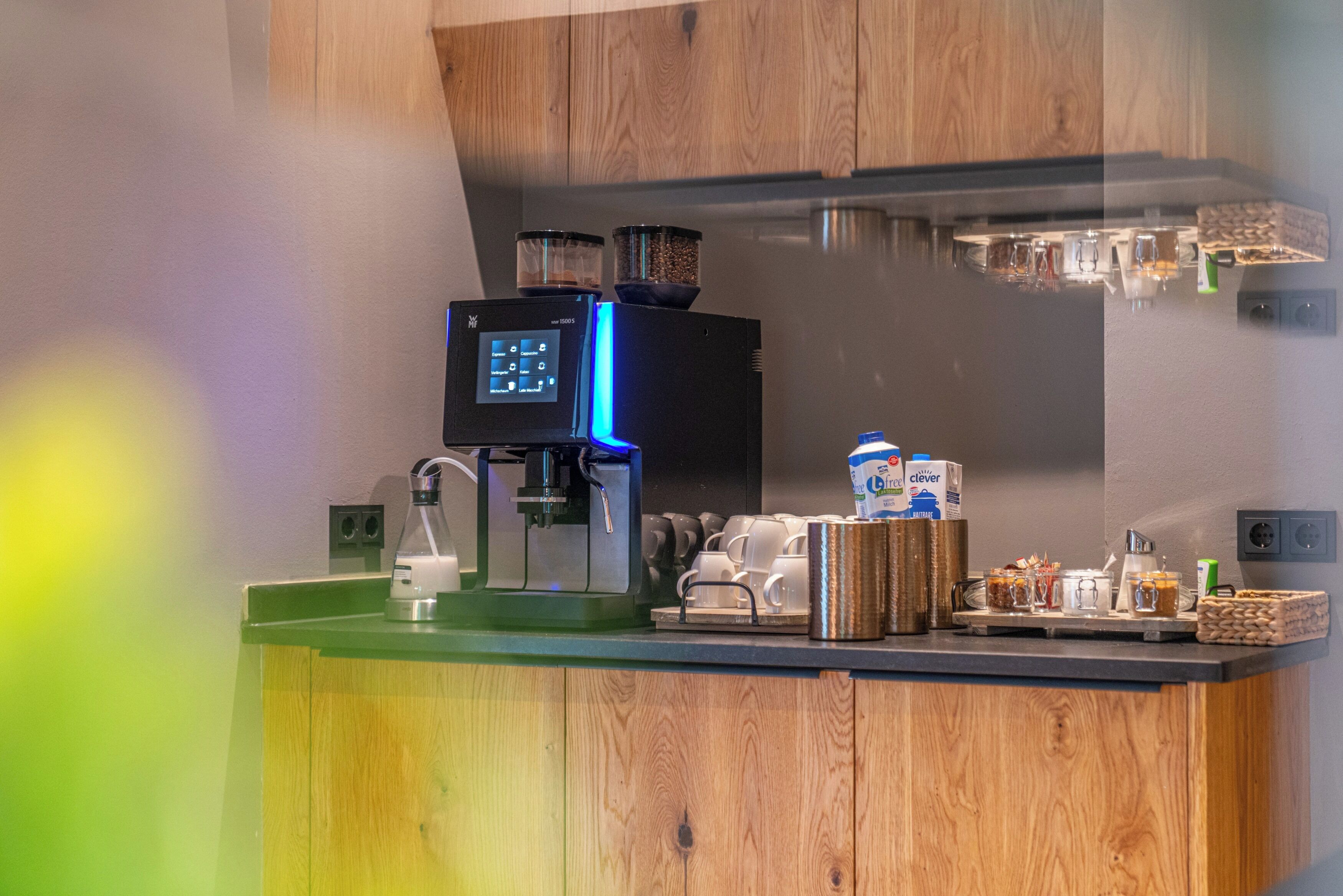A modern kitchen with a coffee machine, a water dispenser, and various kitchen utensils.
