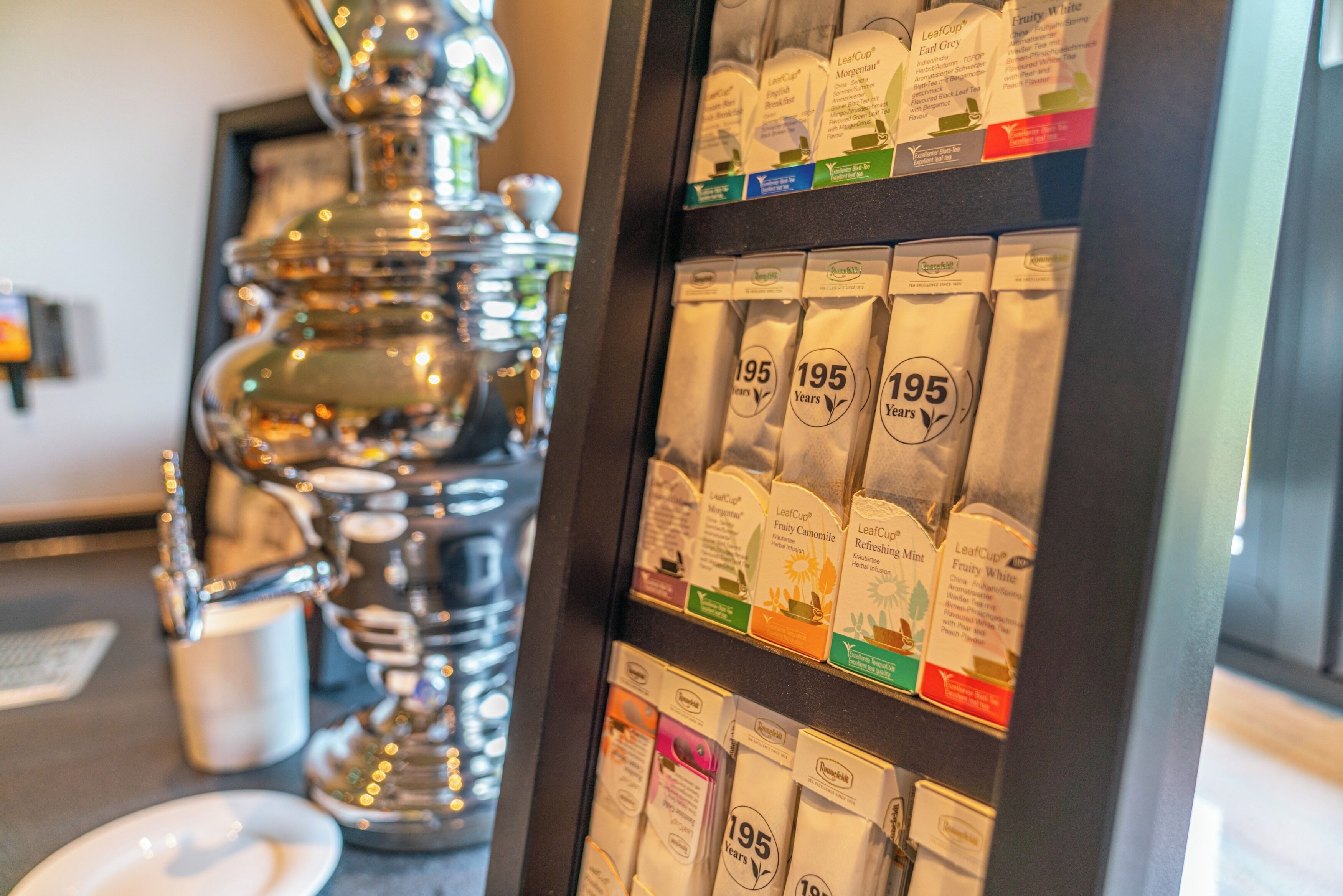Una presentación de bolsitas de té con el texto '195 Años' y una tetera de plata.