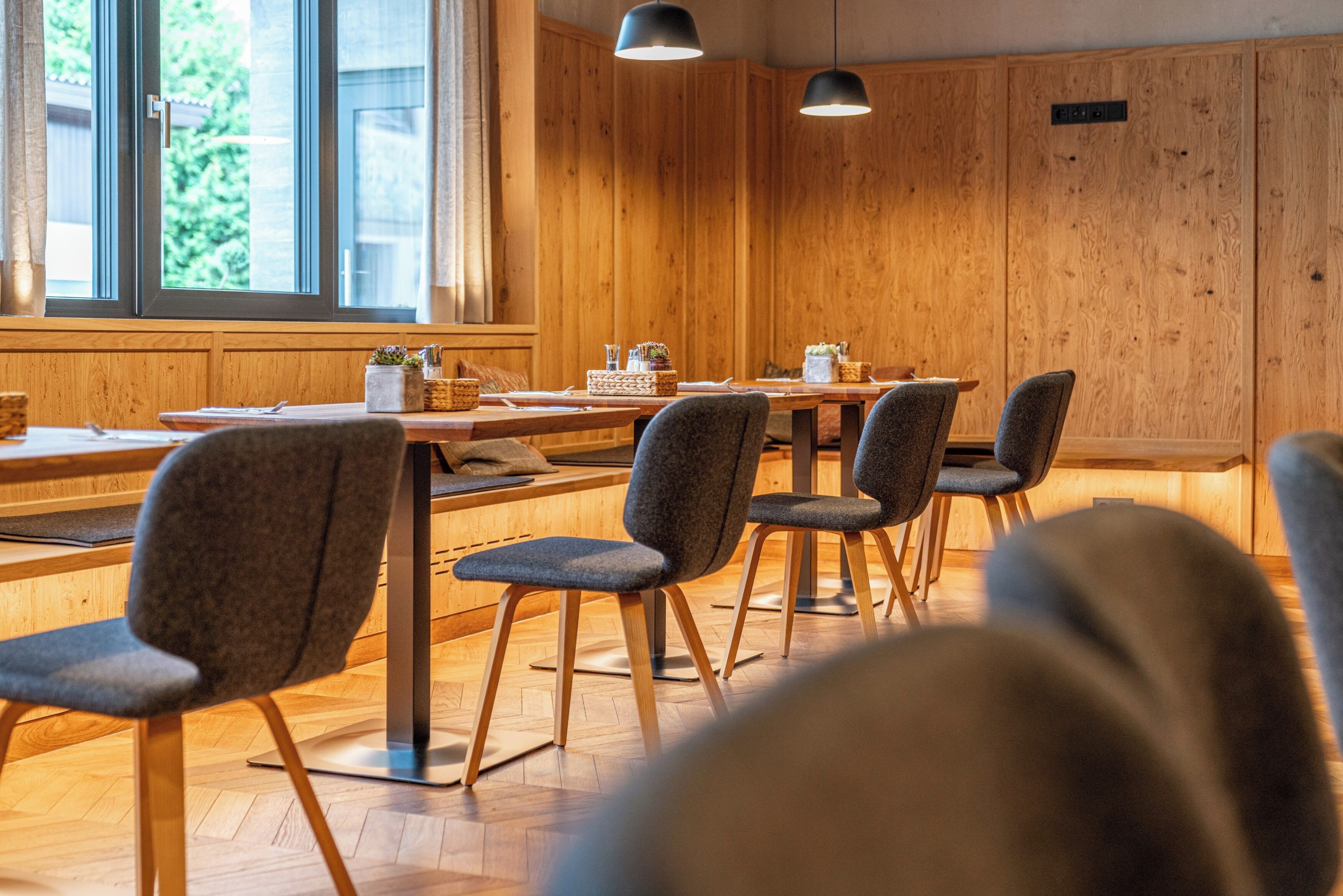 Een eetruimte met houten wanden, een lange tafel en meerdere stoelen.