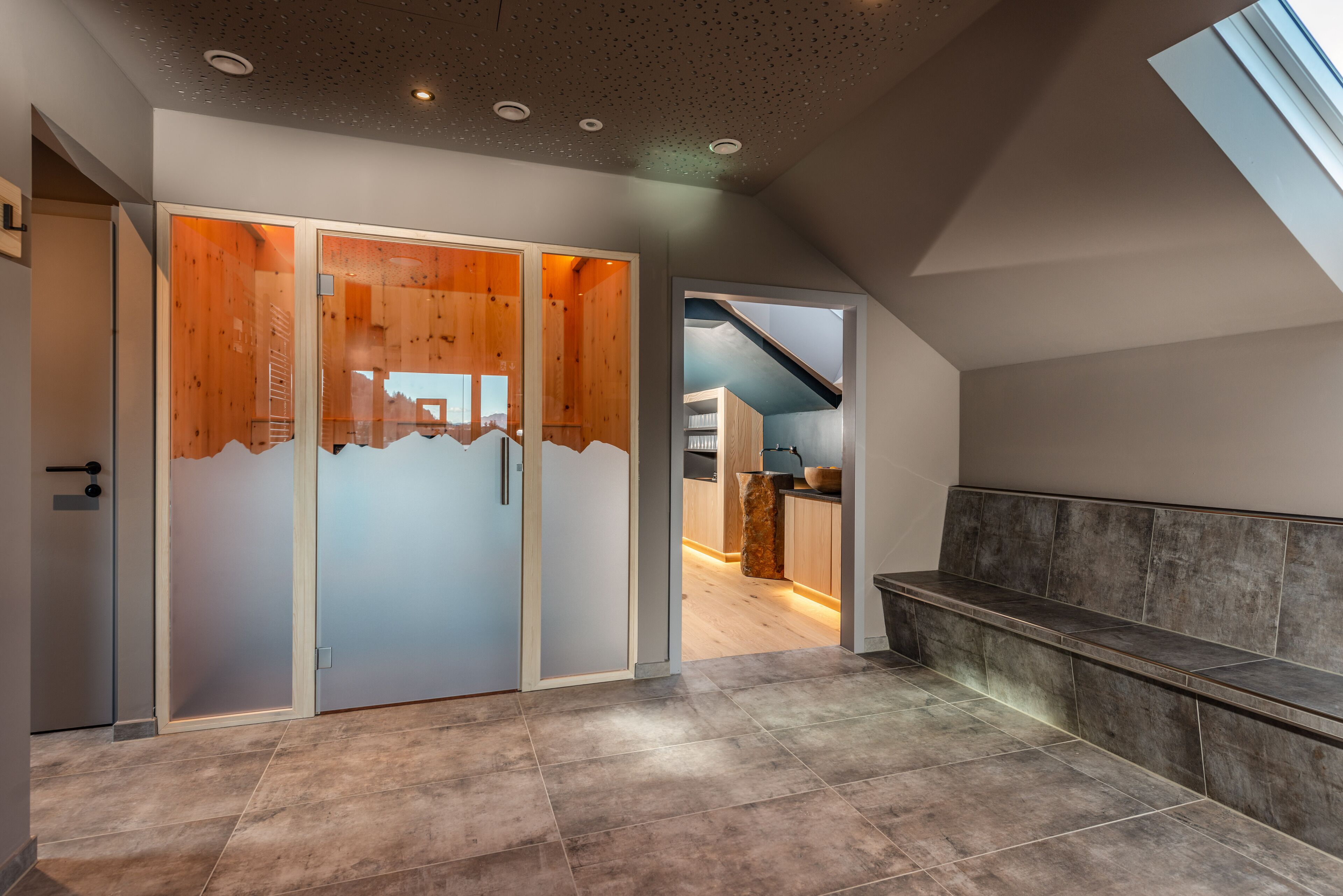 A modern interior with a wooden sliding door, a bench, and a kitchen area visible through an open door.