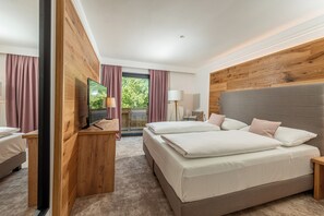 Et moderne hotelværelse med en stor seng, et træhovedgærde og et fjernsyn på et træstel.