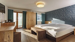 Une chambre d’hôtel moderne avec un grand lit, des meubles en bois, un bureau et une télévision.