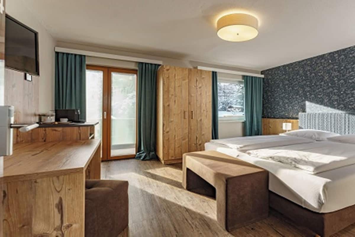 Une chambre d’hôtel moderne avec un grand lit, des meubles en bois, un bureau et une télévision.