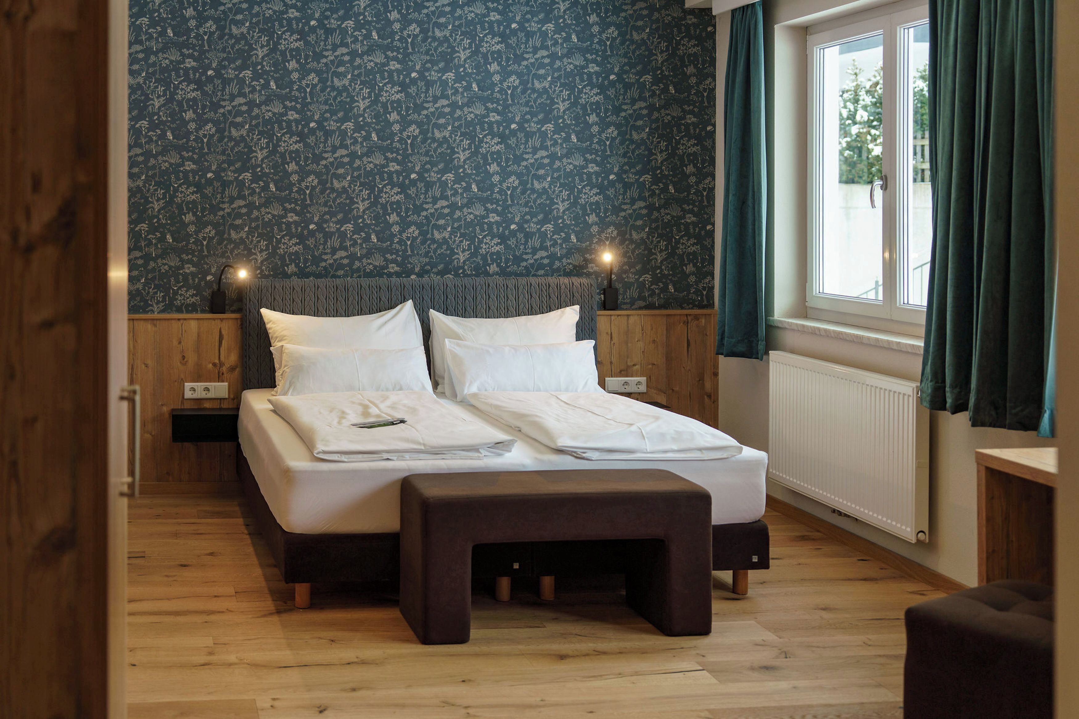 Ein Schlafzimmer mit einem Bett, Holzboden und einem Fenster mit Vorhängen.