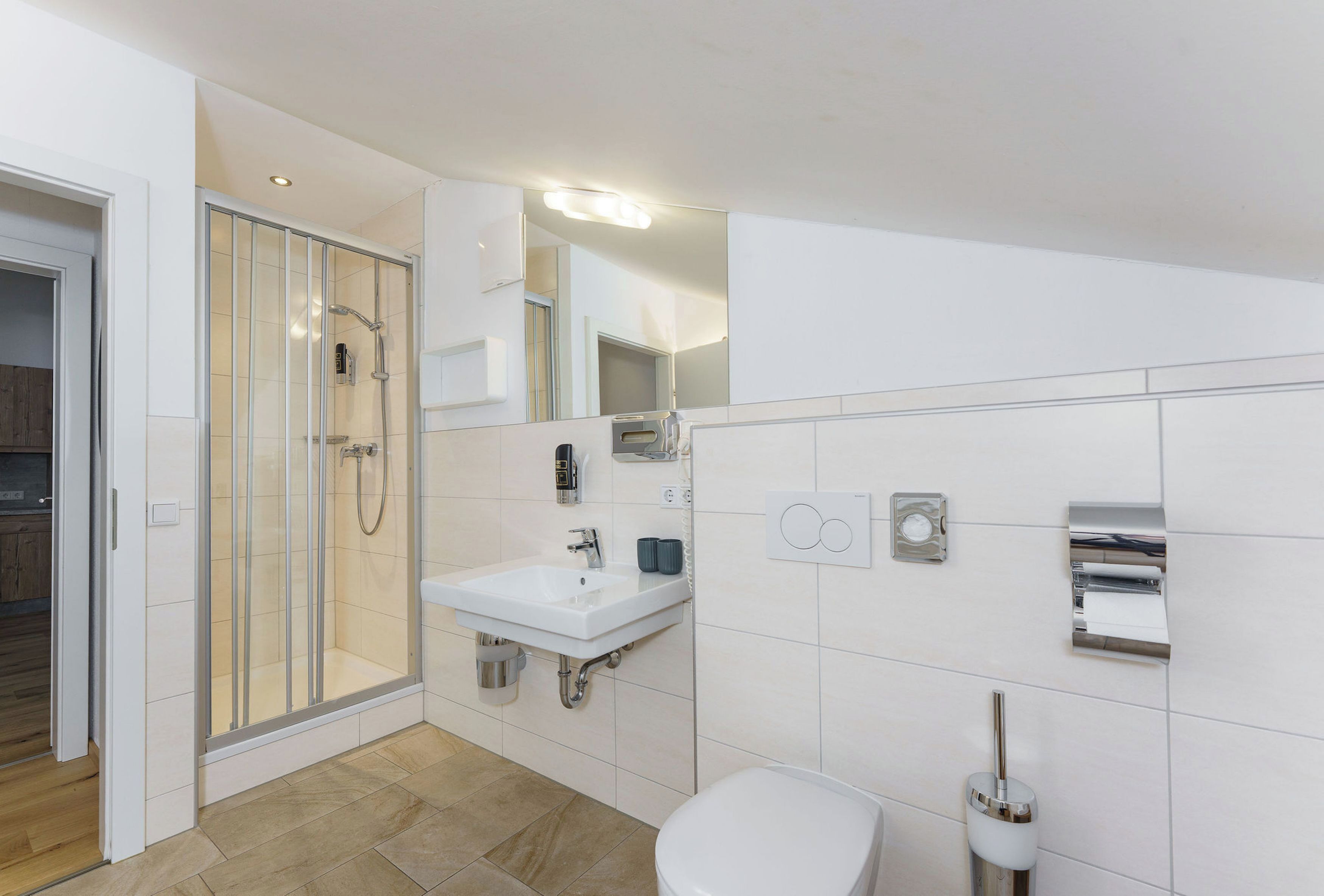 A modern bathroom with a glass-enclosed shower, a white sink, and a toilet.