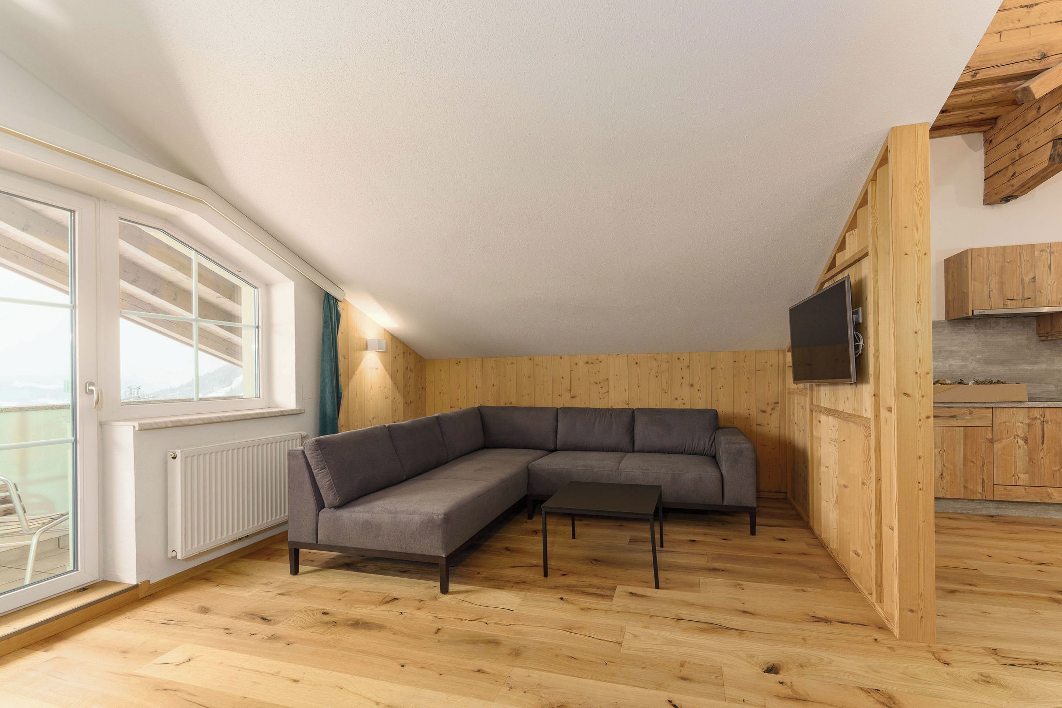 A modern living room with a sectional sofa, a small table, and a TV mounted on the wall.