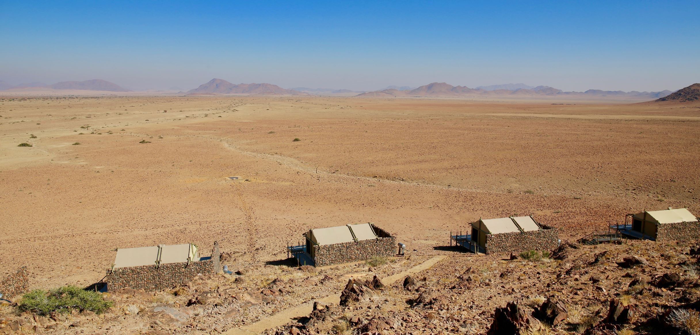 A desert landscape with a few stone buildings, possibly a remote accommodation area.