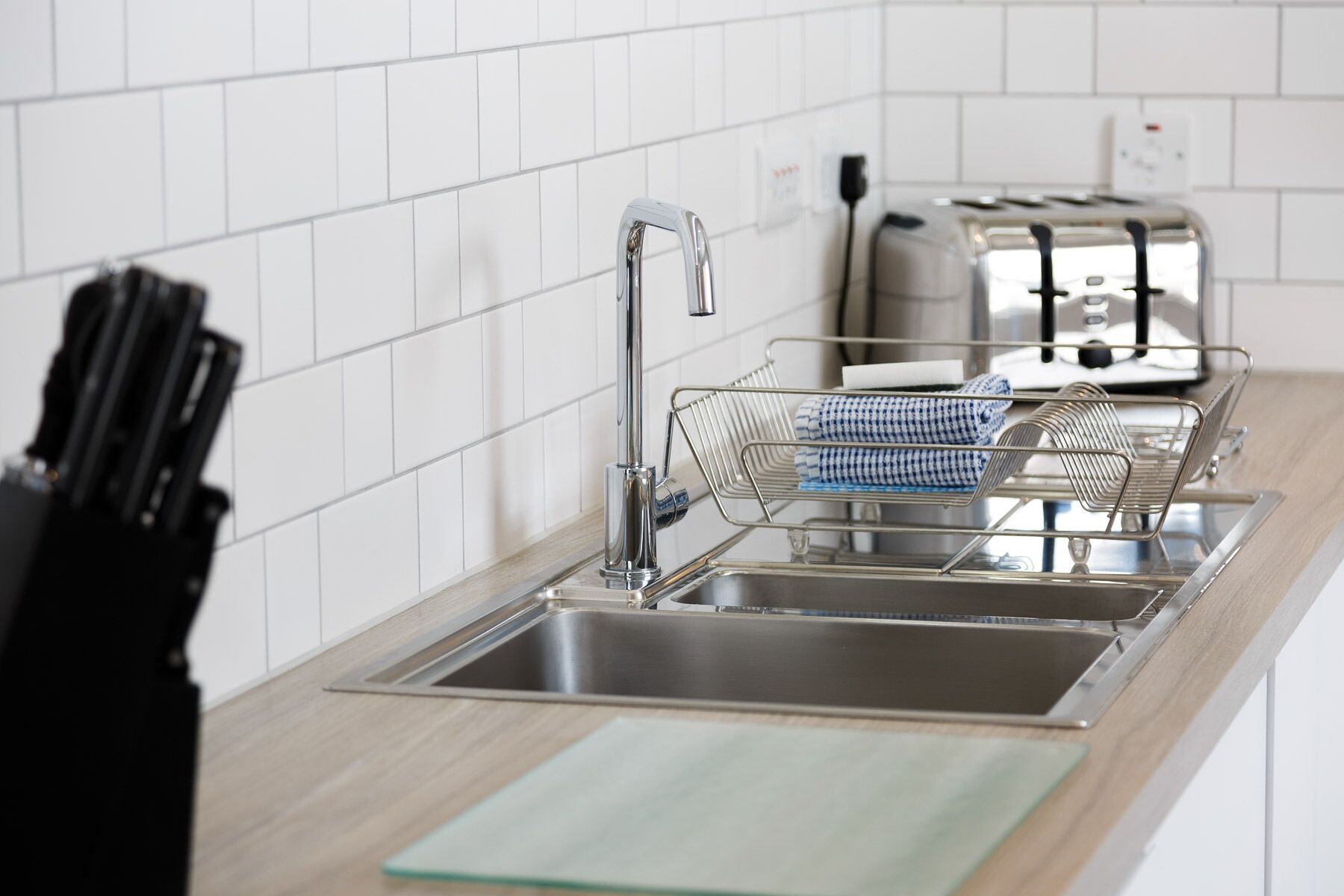 Une cuisine moderne équipée d’un évier en acier inoxydable, d’un bloc à couteaux et d’un grille-pain.