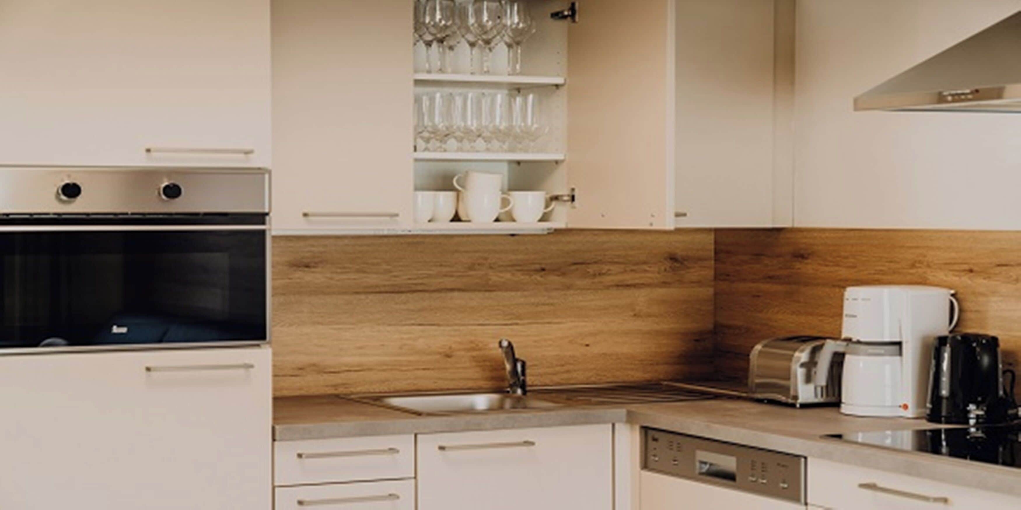 A modern kitchen with a built-in oven, a coffee maker, and a toaster on the countertop.