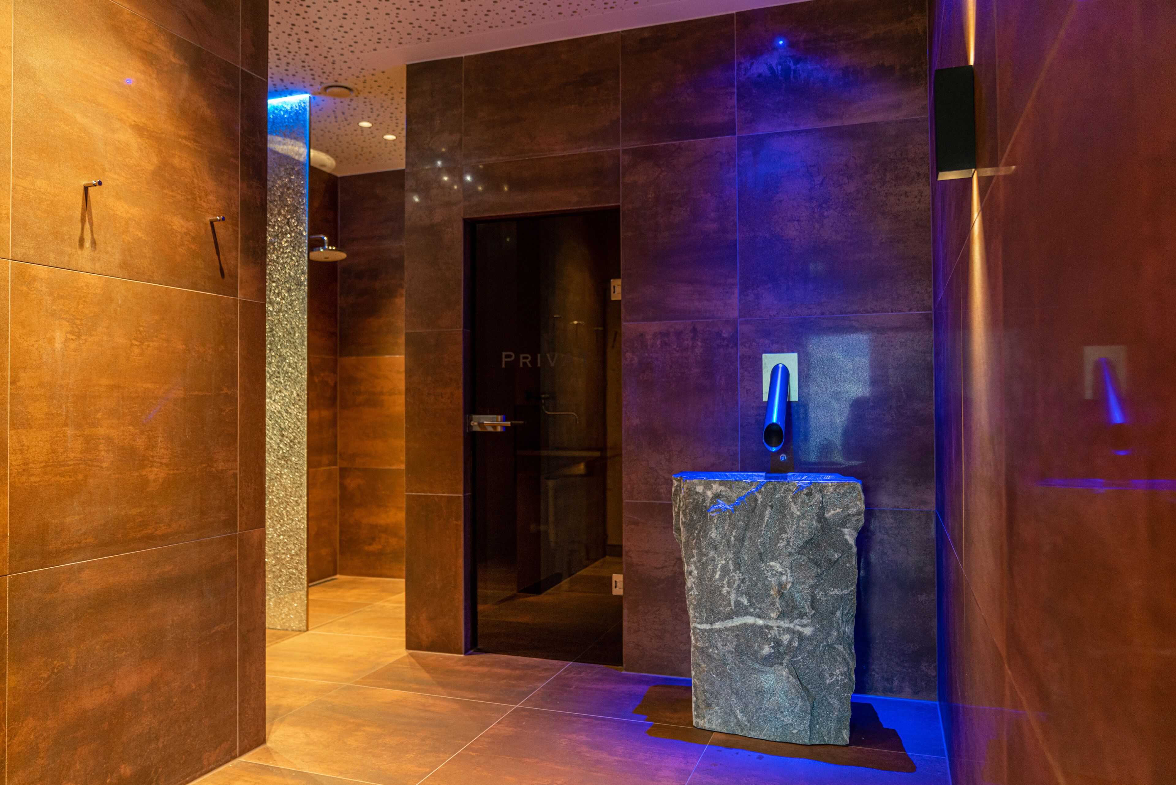 Un bany modern amb un lavabo de pedra, dutxa i senyal de porta privada.