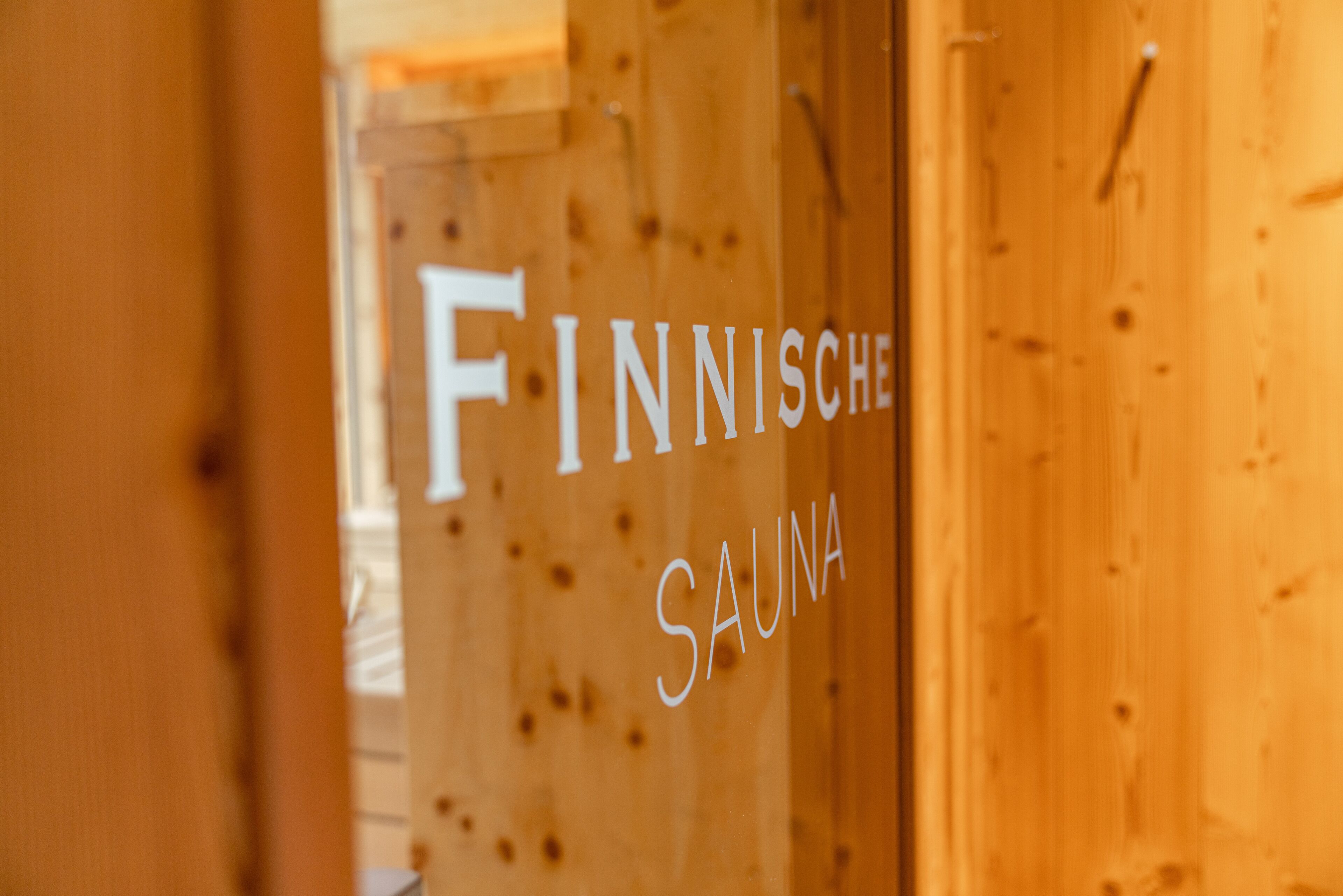 Une porte en bois portant l’inscription « SAUNA FINLANDAISE », indiquant la présence d’un sauna.