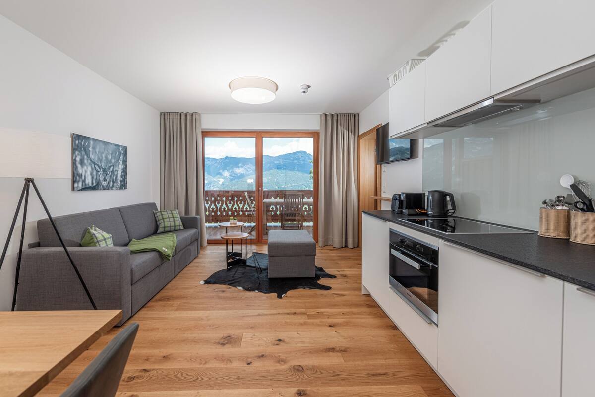 A modern kitchen with a large window, a sofa, and a dining area.