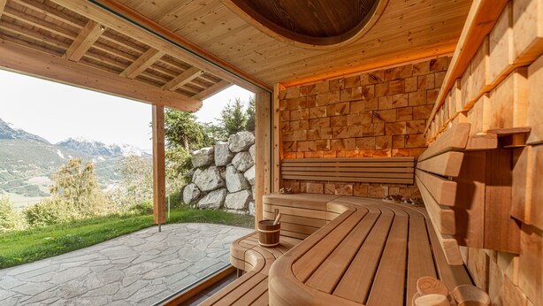 Una sauna de madera con pared de piedra y vista a las montañas.