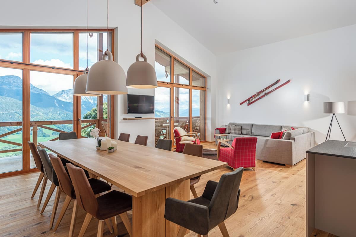 A spacious room with a large wooden dining table, modern chairs, and a cozy seating area with a sofa and armchairs.
