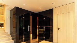 Een modern interieur met een glazen scheidingswand, een houten deur en een trap naar een ander niveau.