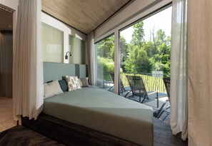 A bedroom with a large bed, a view of the outdoors, and a balcony with chairs. - Erzherzog Johann Alpin Style Hotel - Adults Only, Premium Garni (Schladming)