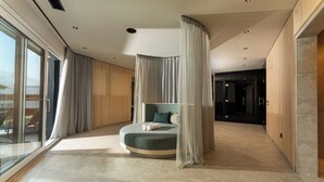 Een moderne slaapkamer met een rond bed, grote ramen en uitzicht op de omgeving.