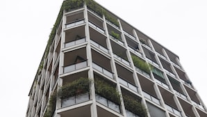 Um edifício com várias andares e varandas, algumas com plantas.