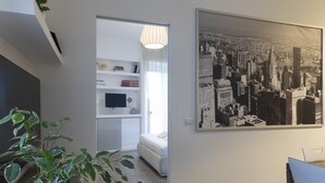 Uma sala de estar moderna com um quadro grande da paisagem urbana, uma televisão de tela plana e uma planta.