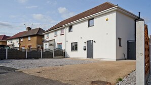 A two-story house with a white exterior and a brown roof. - Newly Refurbished 4 Double Bed House with Parking (Slough)