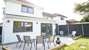 A two-story house with a patio area featuring outdoor seating and a fire pit. - Newly Refurbished 4 Double Bed House with Parking (Slough)