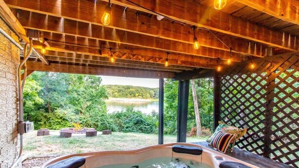 A hot tub with a wooden ceiling and a view of a lake. - Lakefront Escape|Fireplace+Paddleboard+Hottub (North Liberty)